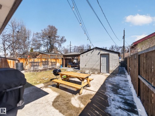 Expansive outdoor space featuring a concrete patio, grassy area, and wood privacy fencing - 11345 89 Street, Edmonton, AB - Outdoor