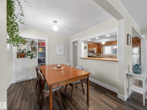 Dining area with wood-finish flooring, built-in shelving, and a pass-through opening to the kitchen - 11345 89 Street, Edmonton, AB - Indoor Photo Showing Dining Room