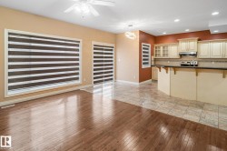 Expansive open-concept living area featuring rich wood-finish flooring and a tiled kitchen space - 