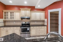Kitchen featuring cream cabinetry, dark granite-style countertops, and a full suite of stainless steel appliances - 
