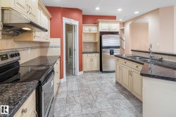 Kitchen featuring cream cabinetry, dark countertops, stainless steel appliances, and a tiled floor - 