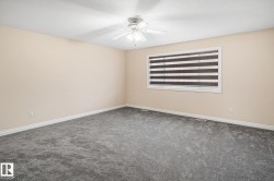 Spacious room featuring neutral wall tones, grey carpeting, a ceiling fan with integrated lighting, and a window with horizontal blinds - 