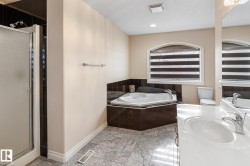 Bathroom featuring a corner jetted tub, a separate glass-enclosed shower, a vanity with a white countertop and integrated sink, chrome fixtures, and patterned floor tiling - 