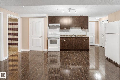 Compact kitchen area featuring dark wood-finish cabinetry, a light-colored countertop, and a white tile backsplash - 3455 29 Street, Edmonton, AB - Indoor Photo Showing Kitchen