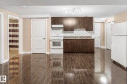 Compact kitchen area featuring dark wood-finish cabinetry, a light-colored countertop, and a white tile backsplash - 