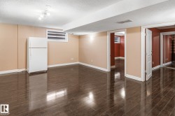 Spacious room featuring dark wood-finish flooring, light tan walls, and white trim - 