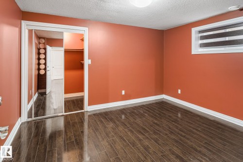 Bedroom featuring wood-finish flooring, vibrant wall color, white baseboards, and a window with blinds - 3455 29 Street, Edmonton, AB - Indoor Photo Showing Other Room