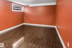 Room featuring wood-finish flooring, white baseboards, and a window with horizontal blinds - 