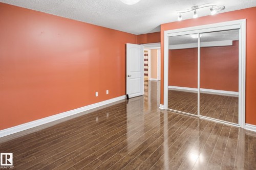 Room with wood-finish flooring, white baseboards, and a mirrored sliding closet door - 3455 29 Street, Edmonton, AB - Indoor Photo Showing Other Room