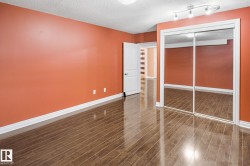 Room with wood-finish flooring, white baseboards, and a mirrored sliding closet door - 