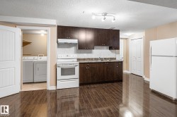 Open-concept kitchen featuring dark wood-finish cabinetry, a white tile backsplash, and a white appliance suite - 