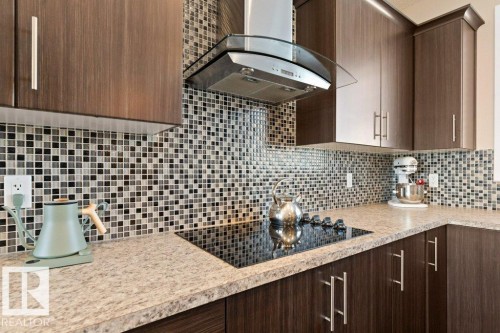 Modern kitchen featuring dark wood-finish cabinetry, a mosaic tile backsplash, and light-toned countertops - 575 Allard Boulevard, Edmonton, AB - Indoor Photo Showing Kitchen With Upgraded Kitchen