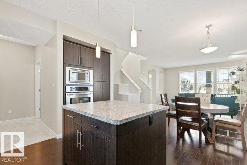 Kitchen island with a light-toned countertop and dark wood-finish cabinetry - 575 Allard Boulevard, Edmonton, AB - Indoor