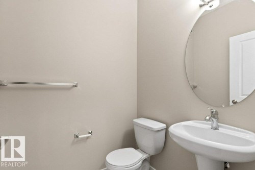Pedestal sink with polished chrome faucet and an oval wall-mounted mirror - 575 Allard Boulevard, Edmonton, AB - Indoor Photo Showing Bathroom