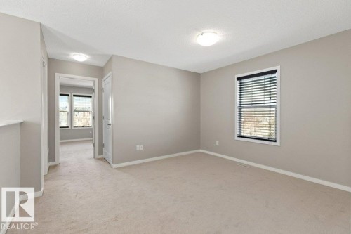 Spacious room featuring neutral carpeting, light gray wall paint, white trim, and a window with blinds - 575 Allard Boulevard, Edmonton, AB - Indoor Photo Showing Other Room