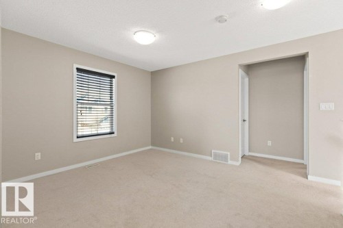 Carpeted room with neutral paint, featuring a window with blinds, ceiling-mounted lighting, and baseboard trim - 575 Allard Boulevard, Edmonton, AB - Indoor Photo Showing Other Room