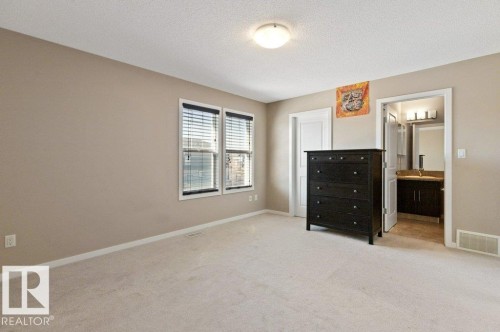 Carpeted room with two windows featuring horizontal blinds, neutral wall paint, and white trim - 575 Allard Boulevard, Edmonton, AB - Indoor
