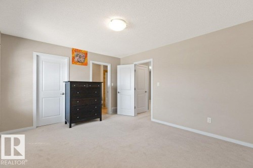Spacious room featuring neutral carpeting, light-toned walls, and a flush-mount ceiling light fixture - 575 Allard Boulevard, Edmonton, AB - Indoor