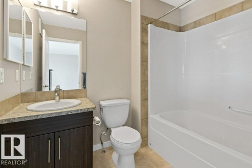 Bathroom featuring a white bathtub with a shower surround, a toilet, and a vanity with a drop-in sink - 575 Allard Boulevard, Edmonton, AB - Indoor Photo Showing Bathroom