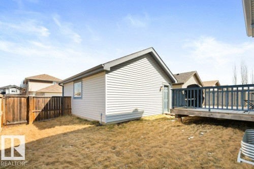Detached accessory building with light-colored siding, a pitched roof, and a single window, accompanied by a wooden deck with dark railings - 575 Allard Boulevard, Edmonton, AB - Outdoor With Deck Patio Veranda With Exterior