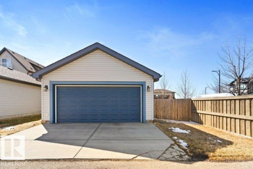 Detached two-car garage with light-colored siding and a blue garage door, featuring an asphalt shingle roof - 575 Allard Boulevard, Edmonton, AB - Outdoor With Exterior