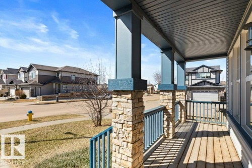 Covered front porch featuring stacked stone pillars and wood-finish flooring - 575 Allard Boulevard, Edmonton, AB - Outdoor With Deck Patio Veranda With Exterior