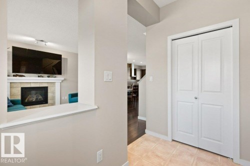 Foyer with bi-fold closet doors, tile flooring, and a pass-through window overlooking the living area - 575 Allard Boulevard, Edmonton, AB - Indoor Photo Showing Other Room With Fireplace