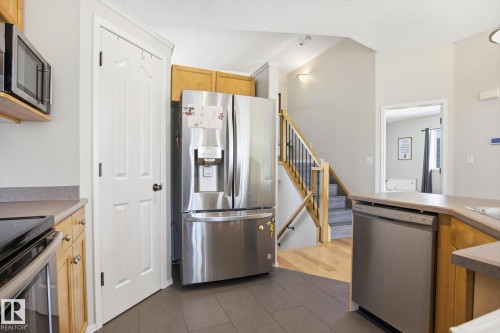 Stainless steel appliances, including a microwave, refrigerator, and dishwasher, complement the wood cabinetry and grey countertops - 2251 Brennan Court, Edmonton, AB - Indoor Photo Showing Kitchen With Stainless Steel Kitchen