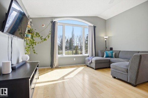Arched picture window with expansive glass, neutral wall tones, vaulted ceiling, and light wood-finish flooring - 2251 Brennan Court, Edmonton, AB - Indoor