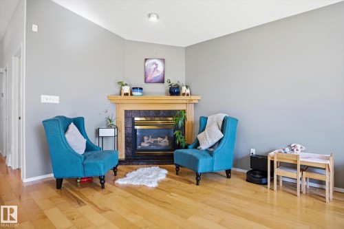 Fireplace featuring a wooden mantel, dark stone surround, and glass enclosure - 2251 Brennan Court, Edmonton, AB - Indoor Photo Showing Living Room With Fireplace