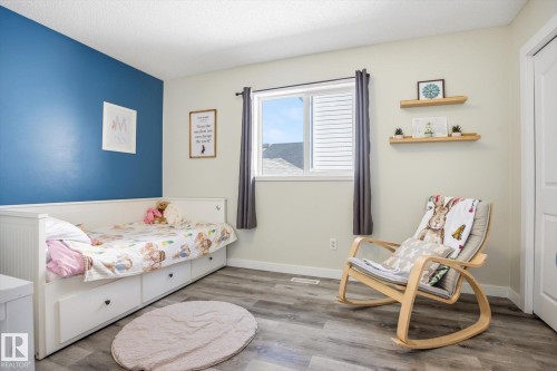 Bedroom featuring a contrasting accent wall, wood-finish flooring, and a window with horizontal blinds - 2251 Brennan Court, Edmonton, AB - Indoor Photo Showing Bedroom