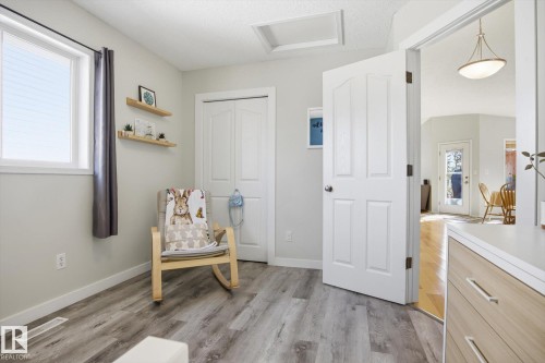 Neutral-toned room featuring wood-finish flooring, a white trim window, a panel door, and bi-fold closet doors - 2251 Brennan Court, Edmonton, AB - Indoor
