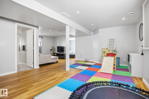 Spacious open-concept lower level featuring wood-finish flooring, recessed lighting, a neutral color palette, and a clear glass shower enclosure visible through an open doorway - 2251 Brennan Court, Edmonton, AB - Indoor Photo Showing Other Room