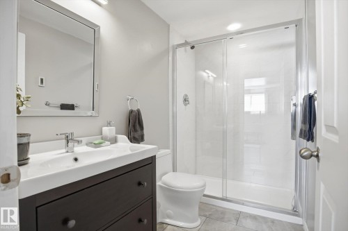 Bathroom featuring a dark wood-finish vanity with a white integrated sink, chrome faucet, and a large framed mirror - 2251 Brennan Court, Edmonton, AB - Indoor Photo Showing Bathroom