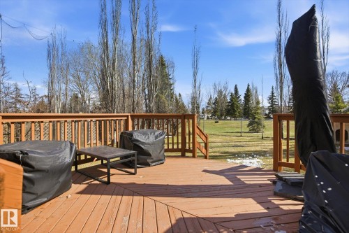 Expansive outdoor wood deck with natural wood railing overlooking a sloped grassy area bordered by mature trees - 2251 Brennan Court, Edmonton, AB - Outdoor With Deck Patio Veranda With Exterior