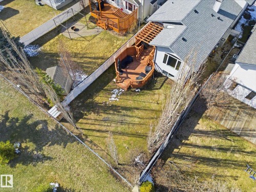 Expansive fenced backyard featuring a multi-level wood deck with pergola, mature trees, and a storage shed - 2251 Brennan Court, Edmonton, AB - Outdoor