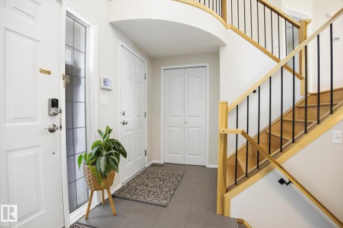 Foyer featuring a curved staircase with natural wood handrails and black iron balusters - 2251 Brennan Court, Edmonton, AB - Indoor Photo Showing Other Room