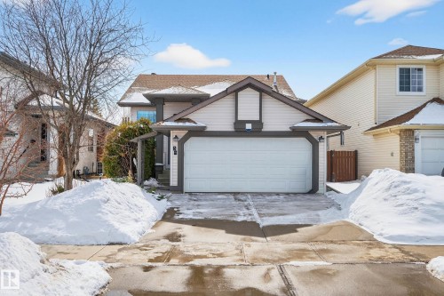 The property features a double garage with a white door, a paved driveway, and light-colored siding with dark trim - 34 Donald Place, St. Albert, AB - Outdoor With Facade