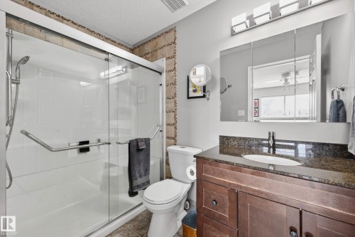 The bathroom features a spacious shower with glass enclosure, a vanity with a dark granite countertop and undermount sink, and a mirrored medicine cabinet with overhead lighting - 34 Donald Place, St. Albert, AB - Indoor Photo Showing Bathroom