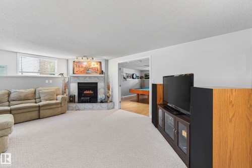 Living area featuring light-colored carpeting, a fireplace with a marble-style surround, and a window with blinds - 34 Donald Place, St. Albert, AB - Indoor Photo Showing Living Room With Fireplace
