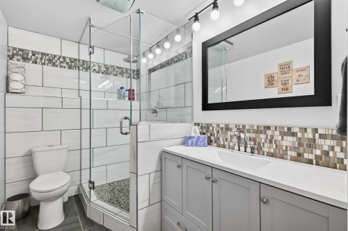 This bathroom features a glass-enclosed shower with a mosaic tile accent and a white toilet - 34 Donald Place, St. Albert, AB - Indoor Photo Showing Bathroom