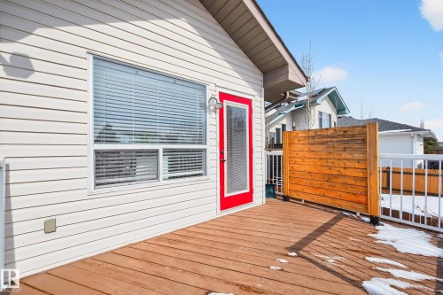 The property features a spacious exterior deck with wood flooring and white railings, a red exterior door, and a horizontal privacy screen - 34 Donald Place, St. Albert, AB - Outdoor With Exterior