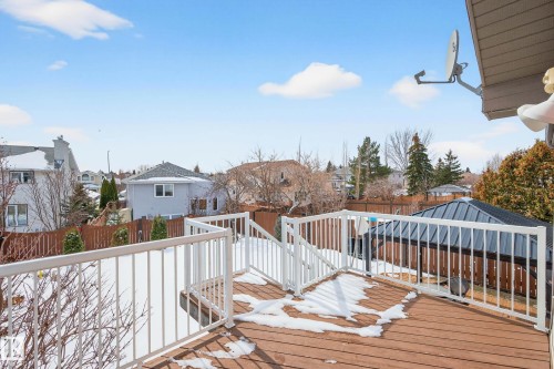 The property features a wooden deck with white railings, offering views of the surrounding neighborhood and a fenced yard with some snow cover - 34 Donald Place, St. Albert, AB - Outdoor With Deck Patio Veranda With Exterior