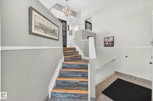 Entryway featuring a multi-toned staircase with white risers and handrails, complemented by a contemporary light fixture overhead - 34 Donald Place, St. Albert, AB - Indoor Photo Showing Other Room