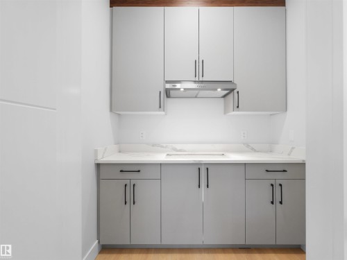 Compact kitchen featuring light gray cabinetry, matte black hardware, and an integrated cooktop - 6722 Crawford Way, Edmonton, AB - Indoor