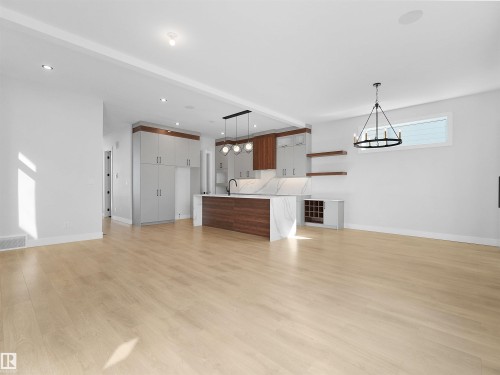 Open-concept living space featuring wood-finish flooring, recessed lighting, and a contemporary chandelier - 6722 Crawford Way, Edmonton, AB - Indoor
