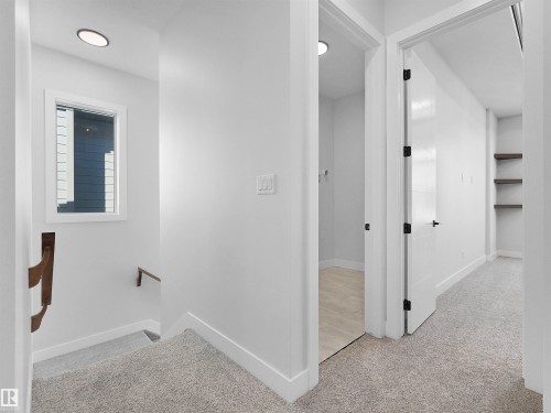 Hallway featuring light-toned carpet flooring, crisp white walls, recessed ceiling lighting, and a window with white trim - 6722 Crawford Way, Edmonton, AB - Indoor Photo Showing Other Room