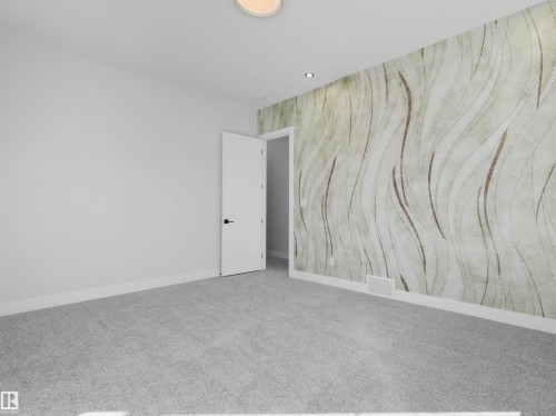 Spacious room featuring light gray carpeting, crisp white baseboards, and a distinctive accent wall with a wavy, textured pattern - 6722 Crawford Way, Edmonton, AB - Indoor Photo Showing Other Room