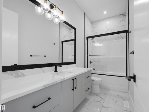 Contemporary bathroom featuring a double vanity with light gray cabinetry and a white countertop, large wall-mounted mirror, and a shower-tub combination with a clear glass enclosure - 6722 Crawford Way, Edmonton, AB - Indoor Photo Showing Bathroom