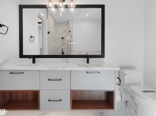 Contemporary bathroom vanity featuring dual integrated sinks, matte black faucets, and a white stone-finish countertop - 6722 Crawford Way, Edmonton, AB - Indoor Photo Showing Bathroom